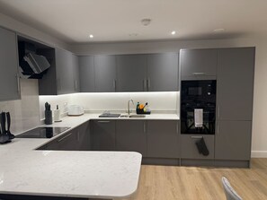 A modern kitchen with grey cabinets, a built-in oven, and a marble countertop. - 1 Bed+Sofa in Sale Near Airport & Trafford Centre (Wythenshawe)
