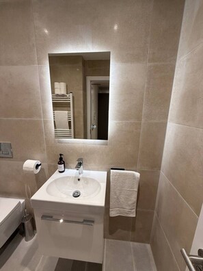 Une salle de bain moderne avec un lavabo blanc, un miroir et un porte-serviettes.