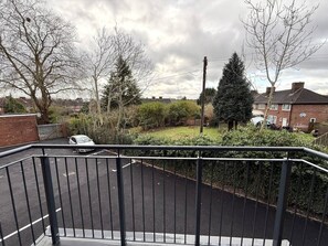 A residential street with a parked car, a metal fence, and houses in the background. - 2 Bed+Sofa in Sale Near Airport & Trafford Centre (Wythenshawe)