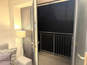 A balcony with a metal railing, a door leading to a room, and a floor lamp. - Twin+Sofa Bed in Sale Nr Airport & Trafford Centre (Wythenshawe)