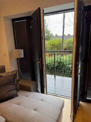 A bedroom with a bed, a chair, a lamp, and a sliding glass door leading to a balcony. - Twin+Sofa Bed in Sale Nr Airport & Trafford Centre (Wythenshawe)