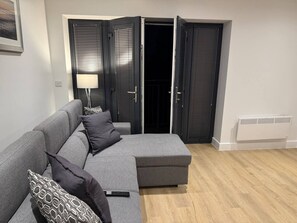 A grey sectional sofa with patterned cushions, a standing lamp, and a remote control on it. - Twin+Sofa Bed in Sale Nr Airport & Trafford Centre (Wythenshawe)