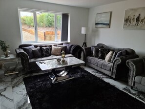 A living room with a sofa set, a coffee table, a lamp, and a view of the outdoors.