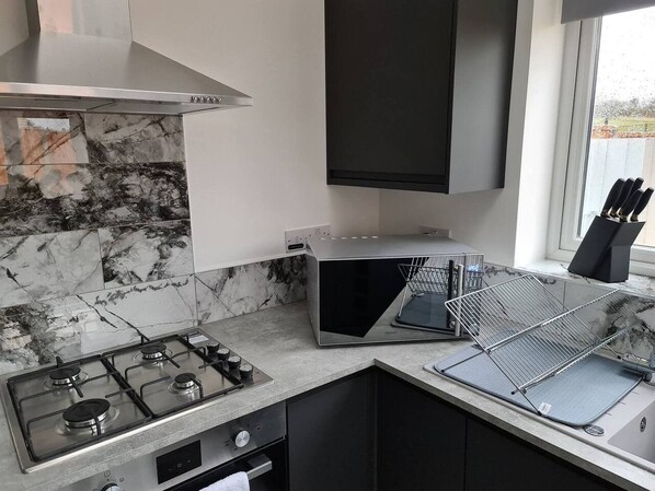 A kitchen with a gas stove, a microwave, and a toaster.
