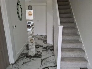 A staircase with a marble floor leading to a room with a bed and a clock on the wall.