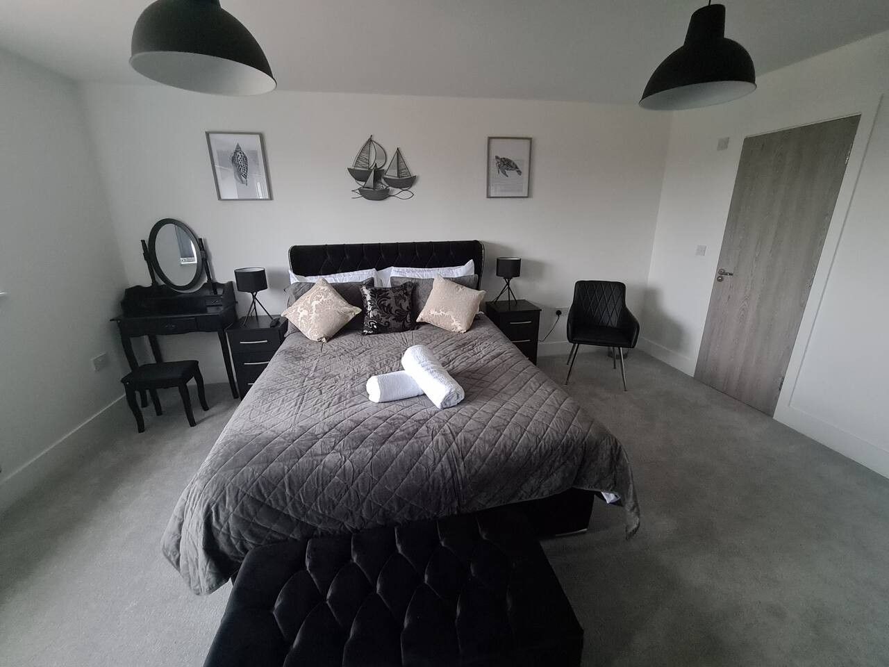 A bedroom with a bed, bedside tables, a desk, and a chair.