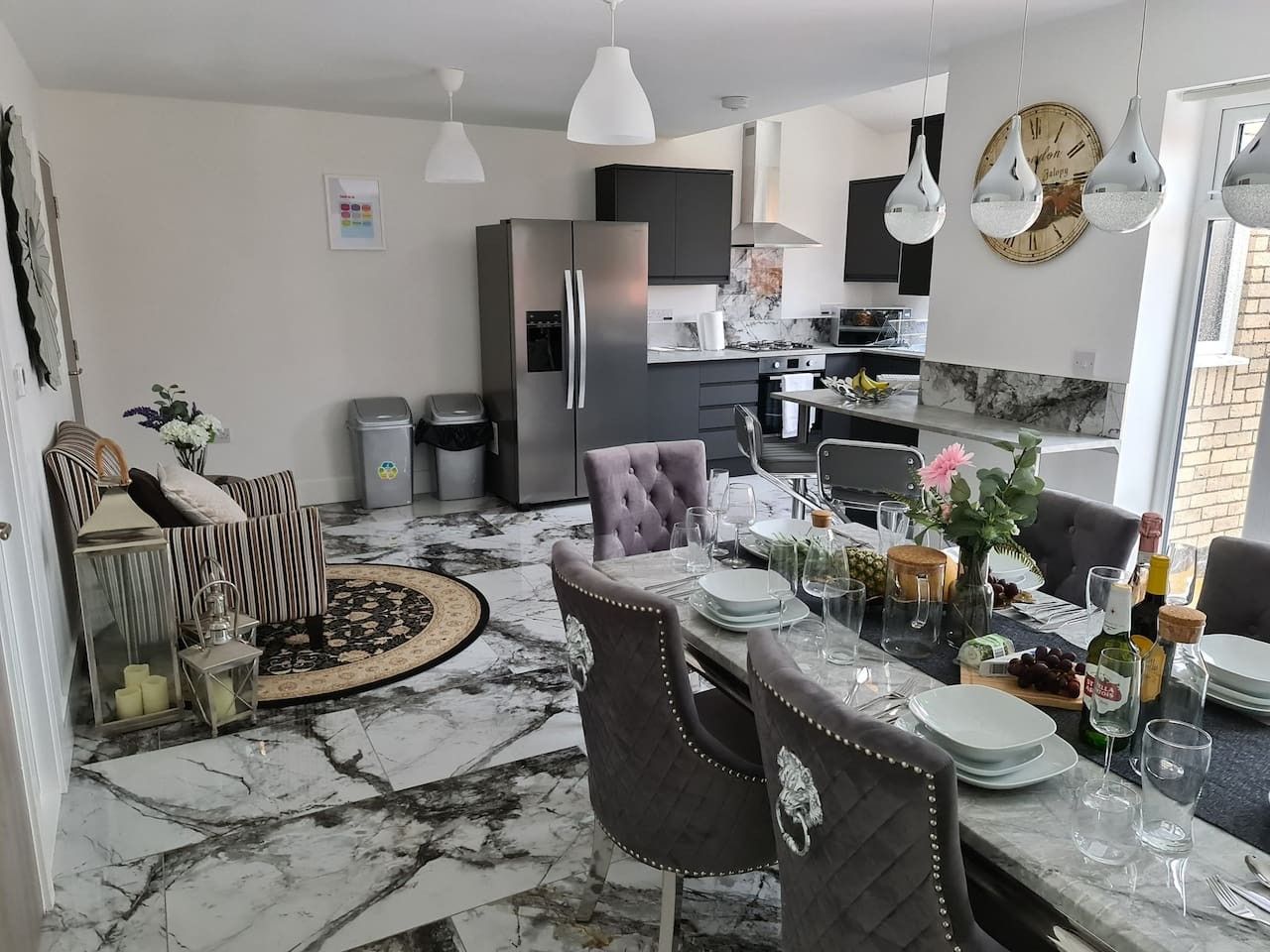 Une cuisine moderne avec un sol en marbre, un coin repas avec des chaises et un réfrigérateur.