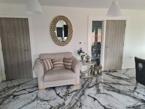 A living room with a beige sofa, a round mirror, and a marble floor. - SAV 5-Bed Executive Detached House, Leicester (Scraptoft)
