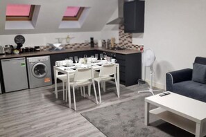 A modern kitchen with a dining area, a washing machine, and a grey sofa. - Sav Apartment Nottingham Road 1 bed Grd flr Flat (Leicestershire)