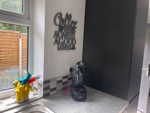 Eine Küche mit Kaffeemaschine, einem Fenster und einer Wanddekoration.