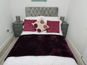 Ein Bett mit einem gesteppten Kopfteil, zwei Nachttische und ein Zierkissen.