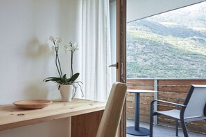 A balcony with a wooden table, a chair, a potted plant, and a view of a mountainous landscape. - Schwarzlehen - Kirchbach (Naturns)