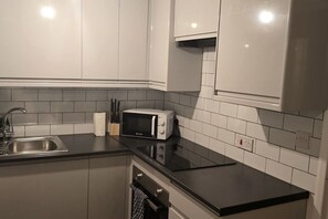 Een keuken met een RVS spoelbak, een magnetron en een vaatwasser.