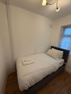 A single bed with a dark headboard, white bedding, and a folded towel on the footboard. - 5 Bed Family home near Heathrow l London (Greater London)