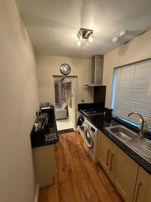A compact kitchen with a washing machine, a coffee machine, and a sink. - 5 Bed Family home near Heathrow l London (Greater London)