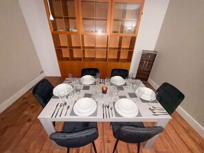 Une table à manger dressée pour quatre personnes, avec des chaises, une bougie et un paravent en bois en arrière-plan.