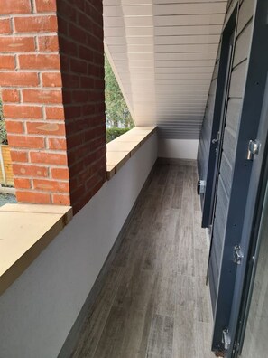 A narrow corridor with a brick wall on one side and a white wall on the other, leading to a dark-colored door. - SAV Stays 2 Bed Flat, Saffron Leicester-1st Floor (Leicester)