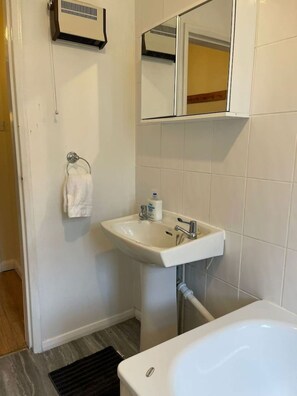 Ein Badezimmer mit einem weißen Waschbecken, einem Spiegel darüber und einer weißen Badewanne.