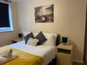 A hotel room with a bed, a painting, a window, and a nightstand with a lamp. - SAV 1-Bed Flat, Walking Distance to Watford Centre (Hertfordshire)