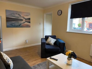A living room with a sofa, a coffee table, a painting, and a clock on the wall. - SAV 1-Bed Flat, Walking Distance to Watford Centre (Hertfordshire)