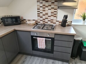 A kitchen with a microwave, stove, oven, and a tiled backsplash.