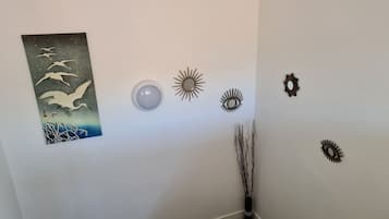 A room with a wall-mounted artwork of birds, a round light fixture, and several wall decorations including sunburst and eye motifs.