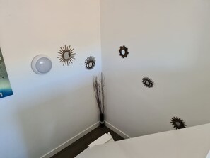 A room with a white wall, a white door, and a white ceiling. There are decorative wall stickers and a vase with branches.