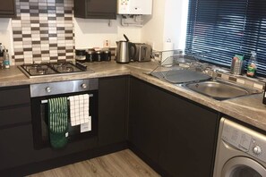 Eine kleine Küche mit Gaskochfeld, Backofen, Spüle und Waschmaschine.