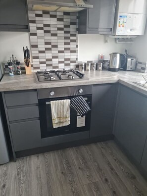 Eine Küche mit einem Gasherd, einem Backofen und einer Mikrowelle.
