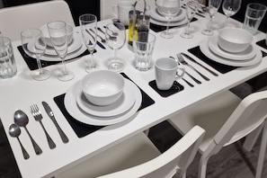 Een gedekte tafel met borden, kommen, bestek, glazen en een waterfles.