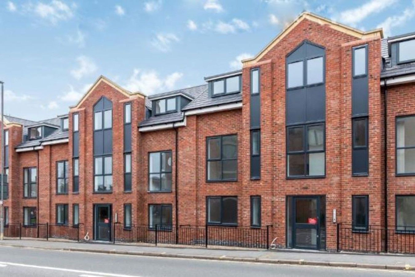 A row of modern brick townhouses with large windows and a flat roof.
