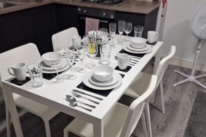 A dining table set with white plates, bowls, glasses, and cutlery. - Sav Apartments Nottingham Road Loughborough - 1Bed (Leicestershire)