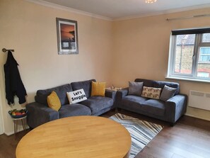 A living room with two sofas, a coffee table, and a window with a view. - Sav Apartments Pretoria Watford - 1 Bedroom (Hertfordshire)