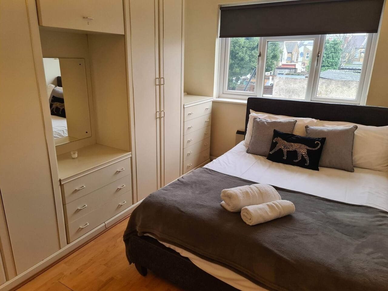 A bedroom with a bed, a wardrobe, a window, and a view of the outside.