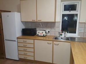 A kitchen with a white refrigerator, a microwave, a toaster, and a sink. - Sav Apartments Pretoria Watford - 1 Bedroom (Hertfordshire)