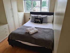 A bedroom with a bed, a window, and a wardrobe. - Sav Apartments Pretoria Watford - 1 Bedroom (Hertfordshire)