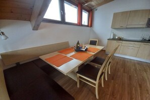 A compact room with a dining table, chairs, a bench, and a kitchenette. - Holiday apartment in Lana with swimming pool (Lana)