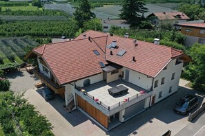 A two-story house with a red-tiled roof, a balcony with a table and chairs, and a car parked in the driveway. - Holiday apartment in Lana with swimming pool (Lana)