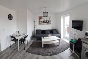 A modern living room with a dining area, a sofa, a coffee table, and a TV. - Sav Apartments Nottingham Road Loughborough - 1Bed (Leicestershire)