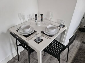 A dining table set for two with plates, cutlery, glasses, and a water glass. - Sav Apartments Nottingham Road Loughborough - 1Bed (Leicestershire)