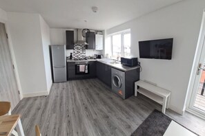 Eine kompakte Küche mit Waschmaschine, Backofen und Mikrowelle.