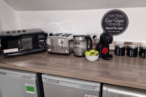 Eine Küche mit Mikrowelle, Toaster, Kaffeemaschine und einer Schüssel Zitronen auf der Arbeitsplatte.