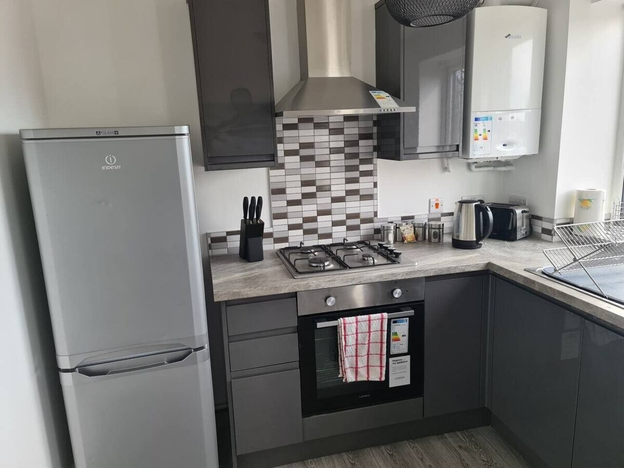 A modern kitchen with a built-in oven, a gas stove, and a stainless steel refrigerator.