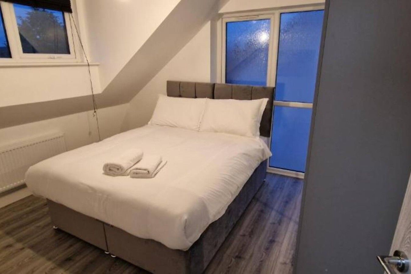 A bedroom with a bed, a window, and a radiator.