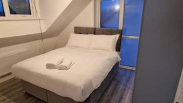 A bedroom with a bed, a window, and a radiator.