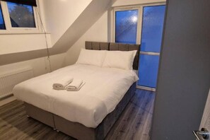 A bedroom with a bed, a window, and a radiator. - Sav Apartments Nottingham Road Loughborough - 1Bed (Leicestershire)