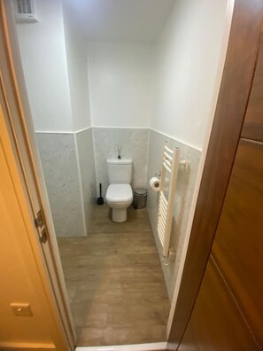 A small, narrow bathroom with a toilet, a bidet, and a trash bin. - SAV Regent Leicester: Luxury Studio Apartment (Leicester)