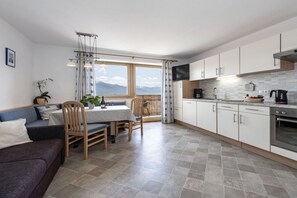 Et moderne køkken med hvide skabe, et spiseområde med bord og stole samt en sofa.