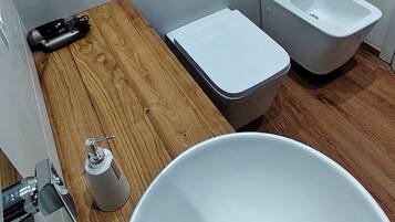 Ein Badezimmer mit einem weißen Waschbecken, einem Bidet und einer Toilette.