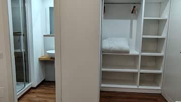Ein Schlafzimmer mit Holzboden, einem Bett, einem Kleiderschrank und einer Klimaanlage.